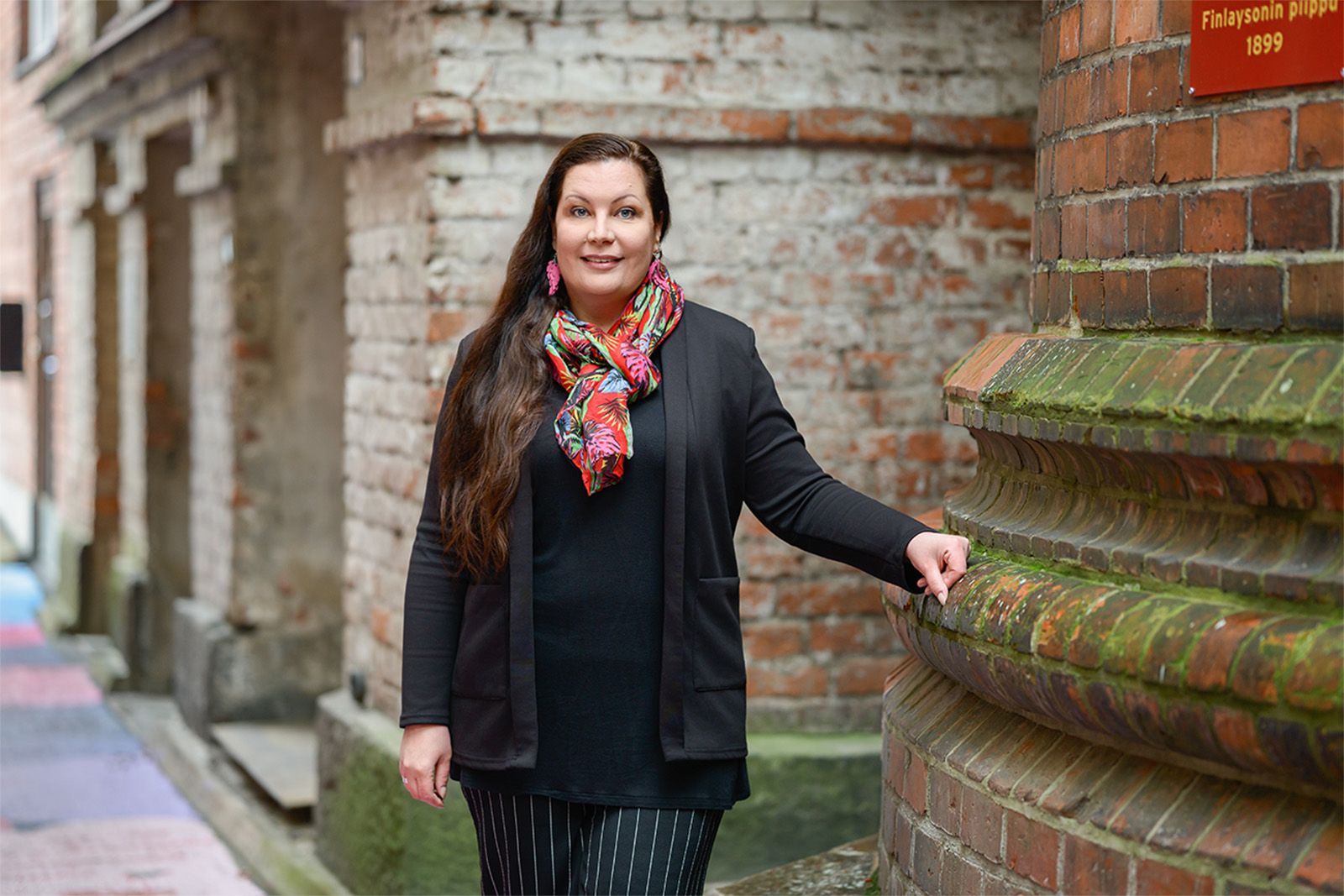 01 lissu-veittikoski_by_mikko-vares_kulttuuritoimitus Nainen hymyilee kameralle pienellä vanhalla kujalla.