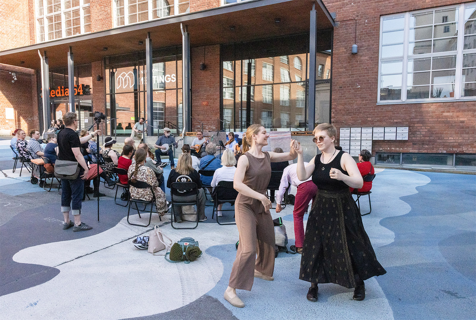 Tanssipari vauhdissa, takana yleisöä ja yhtye esiintymässä ulkolavalla.